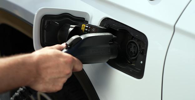 A person plugging a charger into an electric vehicle.