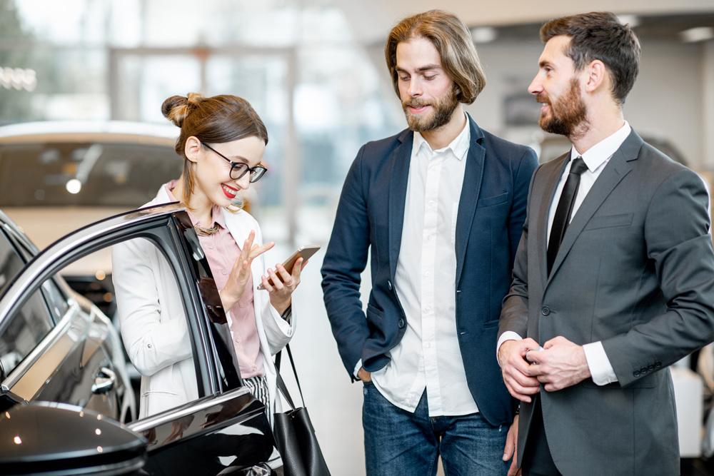 Couple and salesperson looking at car