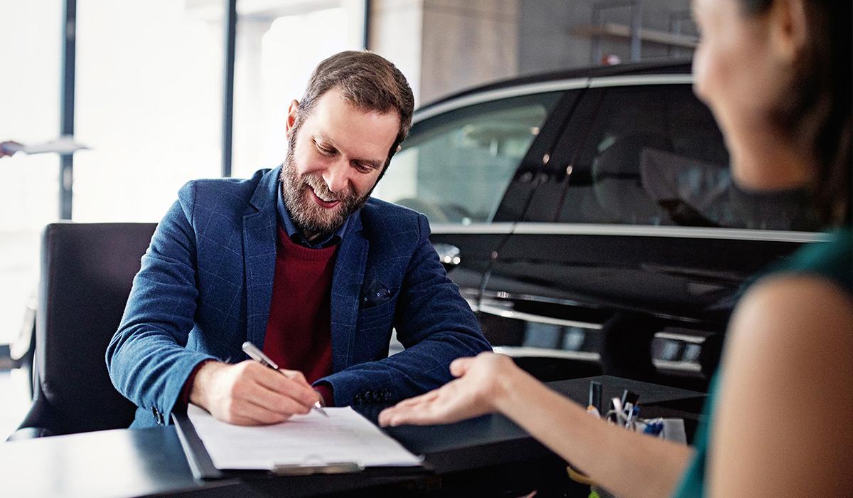 man sitting at desk filling out car purchase paperwork