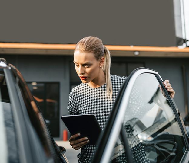 Person inspecting auto with tablet